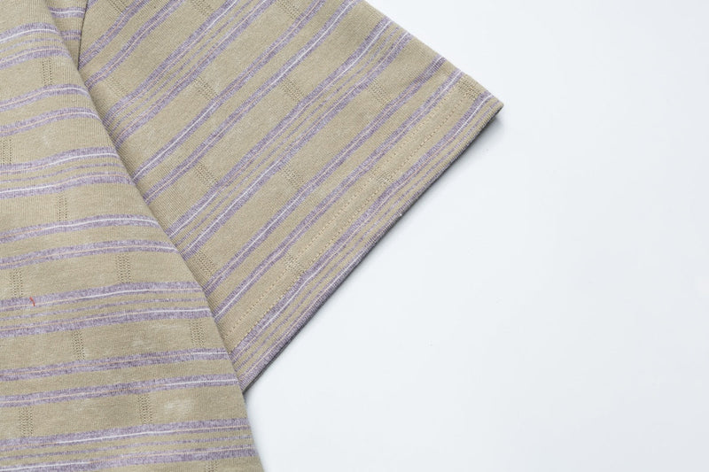 Beige striped ringer t-shirt with lavender bands, shown folded on a clean white background