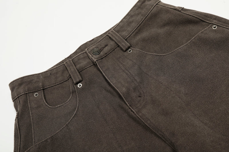 Close-up of brown pants waist with belt loops, button closure, and pocket seams