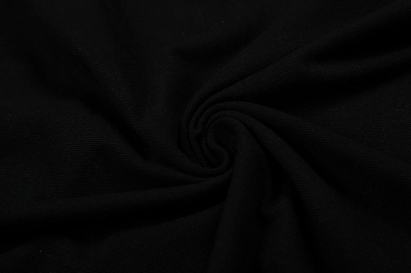 Black textured polo shirt fabric with a subtle woven knit pattern and soft folded drape for a classic menswear look