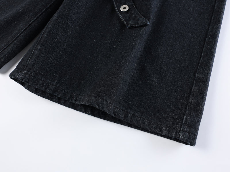 Lower hem and side seam of black denim shorts with wide-leg cut