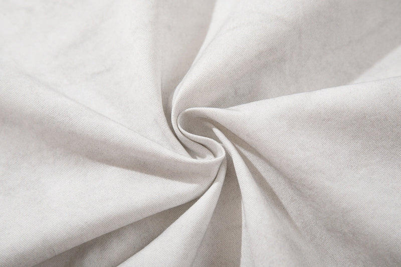 Close-up of white cotton fabric with a soft twisted swirl texture on a short sleeve shirt
