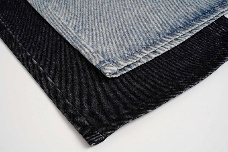 Close-up of stacked black and light wash jeans hems