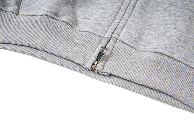 Close-up of bottom hem and zipper on light gray fleece hoodie
