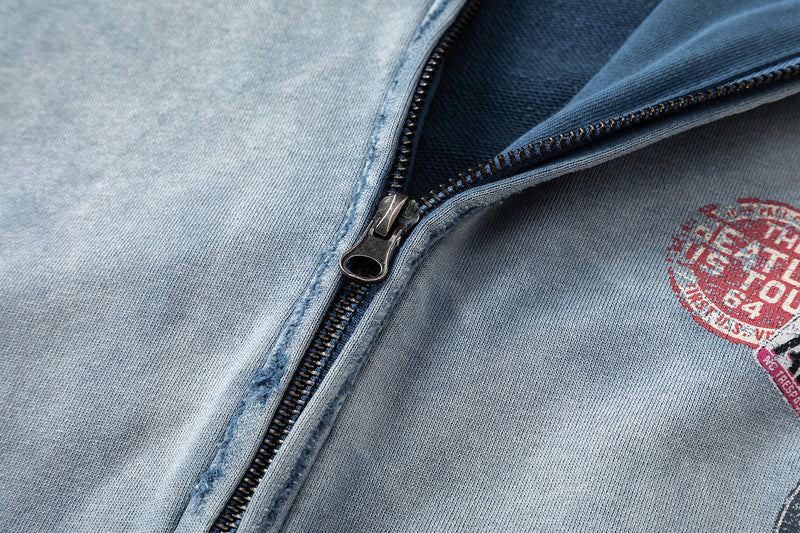 Close-up of washed blue hoodie zipper and chest patch on soft cotton fabric