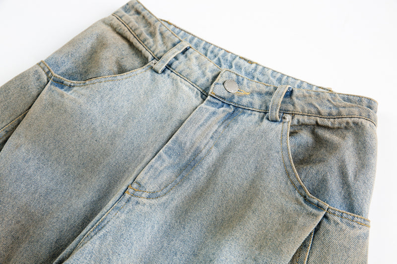 Close-up of the front waistband and pocket area on faded light blue denim jeans