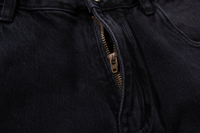 Close-up of dark wash jeans front zipper with gold-tone zipper teeth