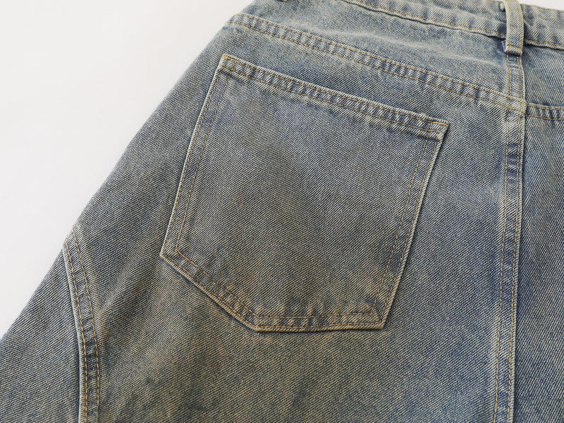 Close-up of the back pocket on faded blue denim pants with contrast topstitching and faded denim wash
