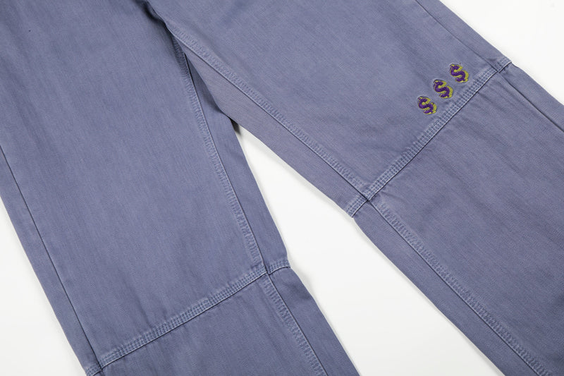 Close-up of the lower leg on blue carpenter pants with embroidered dollar signs