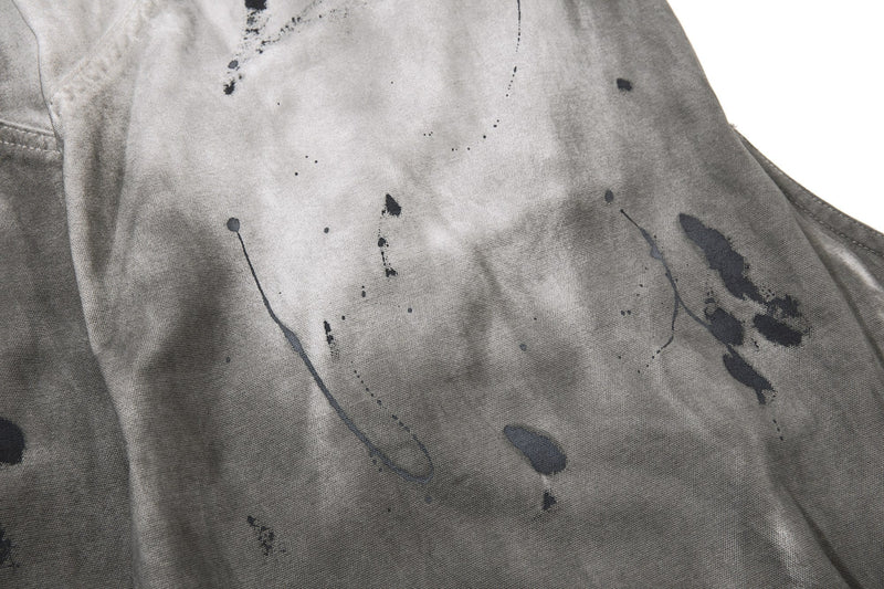 Close-up of gray denim leg with scattered black paint-like splatter