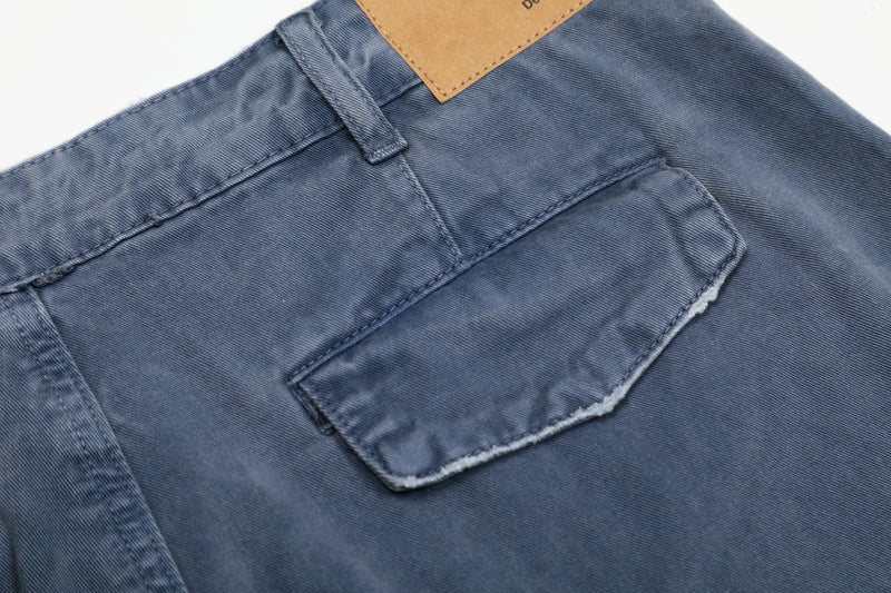 Close-up of back pocket on washed blue cargo pants with frayed pocket edge