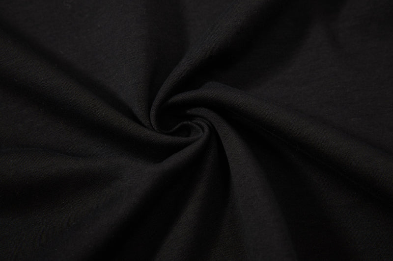 Black textured polo tee fabric with a close-up swirl fold, showing a sleek streetwear knit finish