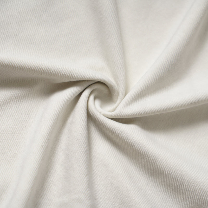 Close-up of cream knit fabric gathered in a twist showing the tee texture