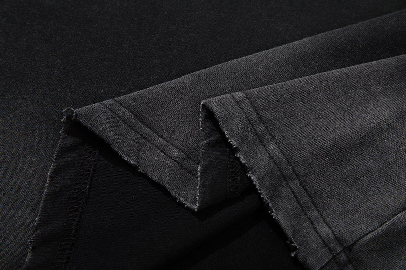Black washed graphic tee fabric close-up with frayed edges and soft worn texture, showcasing a streetwear style finish