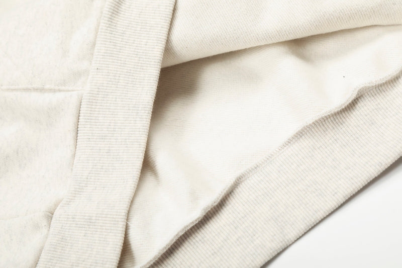 Close-up of cream hoodie seam and ribbed trim with soft fleece texture