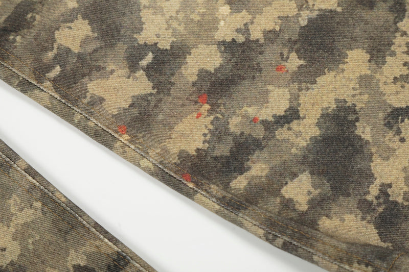 Close-up of camo denim lower leg with stitched hem and small red specks