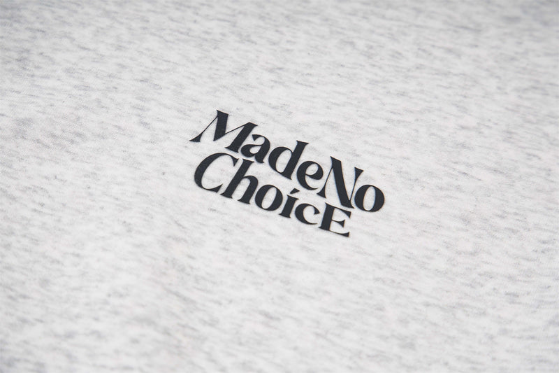 Close-up of MadeNoChoice logo printed on light gray hoodie fabric