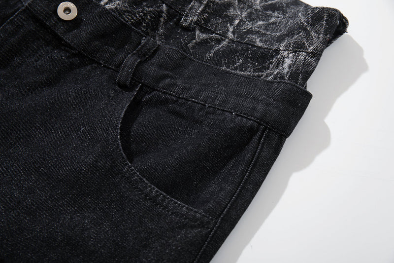Close-up of black denim side pocket, waistband button, and cracked panel trim
