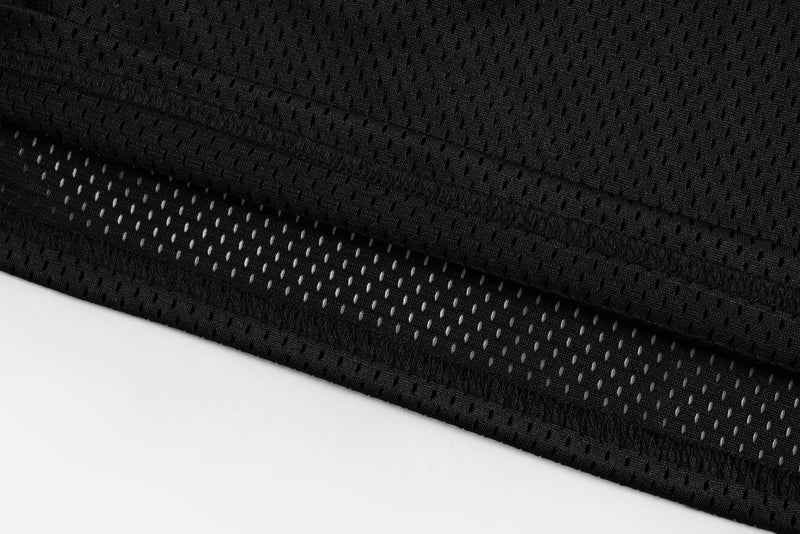 Close-up of black mesh football jersey fabric with breathable perforations and stitched hem detailing