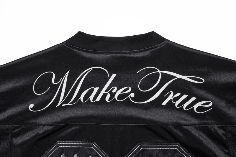 Upper back of black jersey showing Make True script across the yoke