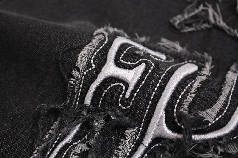 Close-up of a black washed T-shirt with frayed distressed star patch embroidery and stitched graphic detailing