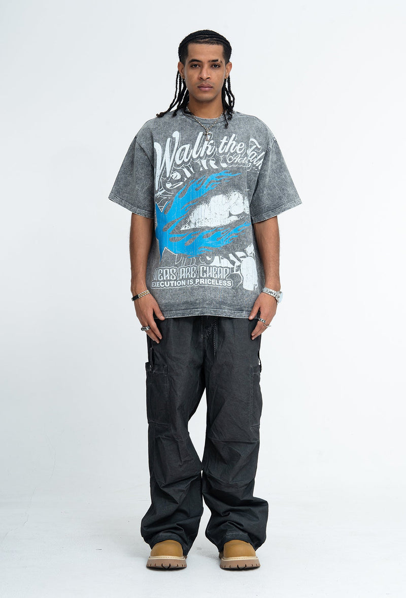 Model wearing a vintage washed gray graphic T-shirt with bold blue and white print, paired with black cargo pants and tan boots