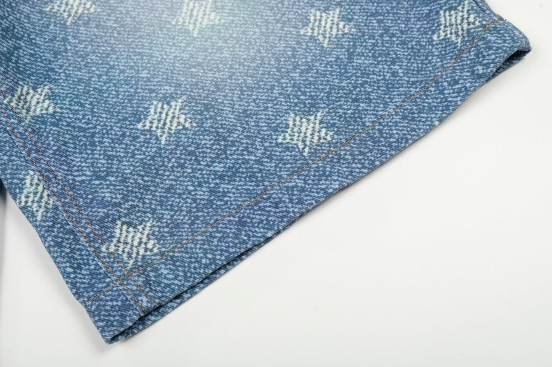 Close-up of hem on blue star-wash denim shorts with stitched edge and faded print