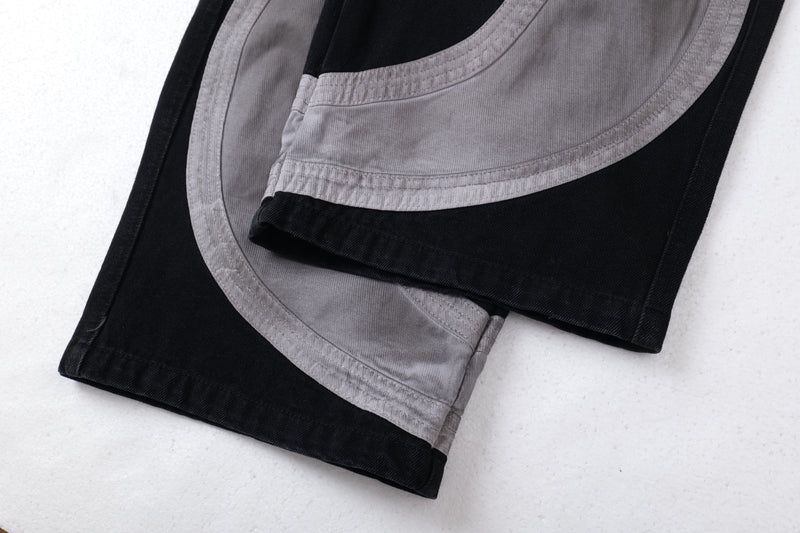 Folded hem detail of gray and black cargo pants with curved stitched panel edges