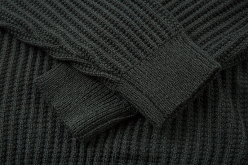 Close-up of knit sweater sleeve and ribbed stitch texture in dark green