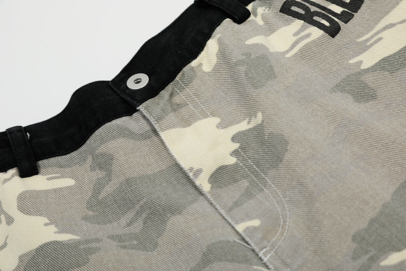 Close-up of black waistband, snap detail, and camo fabric seam on wide-leg jorts