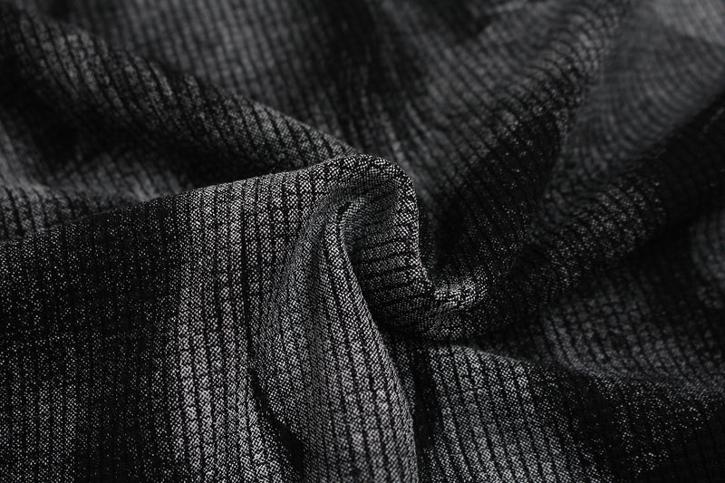 Close-up of black textured fabric with a shadowy portrait print, showing the tee’s dark graphic and studded mock-neck style