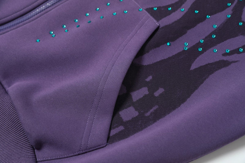 Close-up of purple hoodie pocket and flame graphic with teal rhinestones