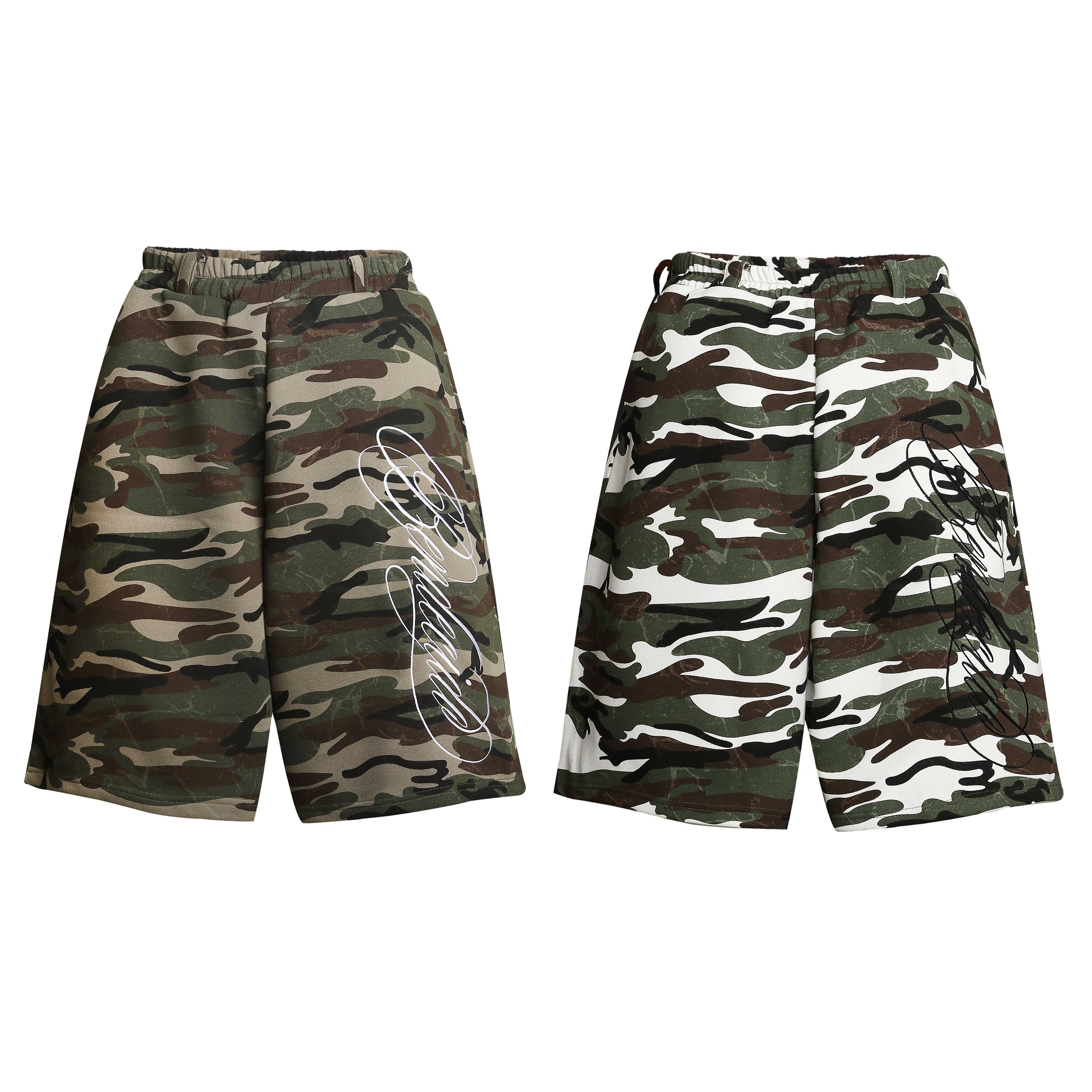 Omirad woodland camo print loose shorts with white script logo, front view on white background