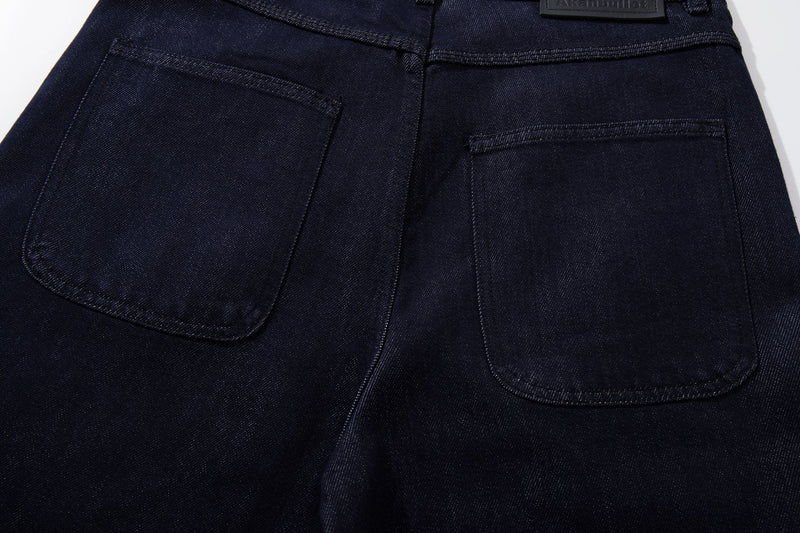 Back pockets of dark wash jeans with top stitching, close-up view