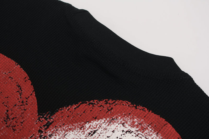 Close-up of a black ribbed graphic tee with a distressed red and white melted heart ribcage print