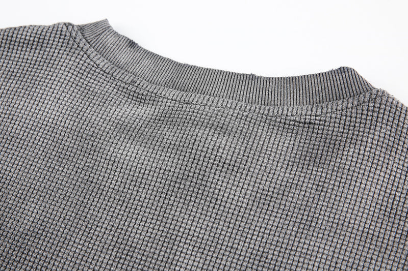 Close-up of gray waffle knit fabric and ribbed crew neckline