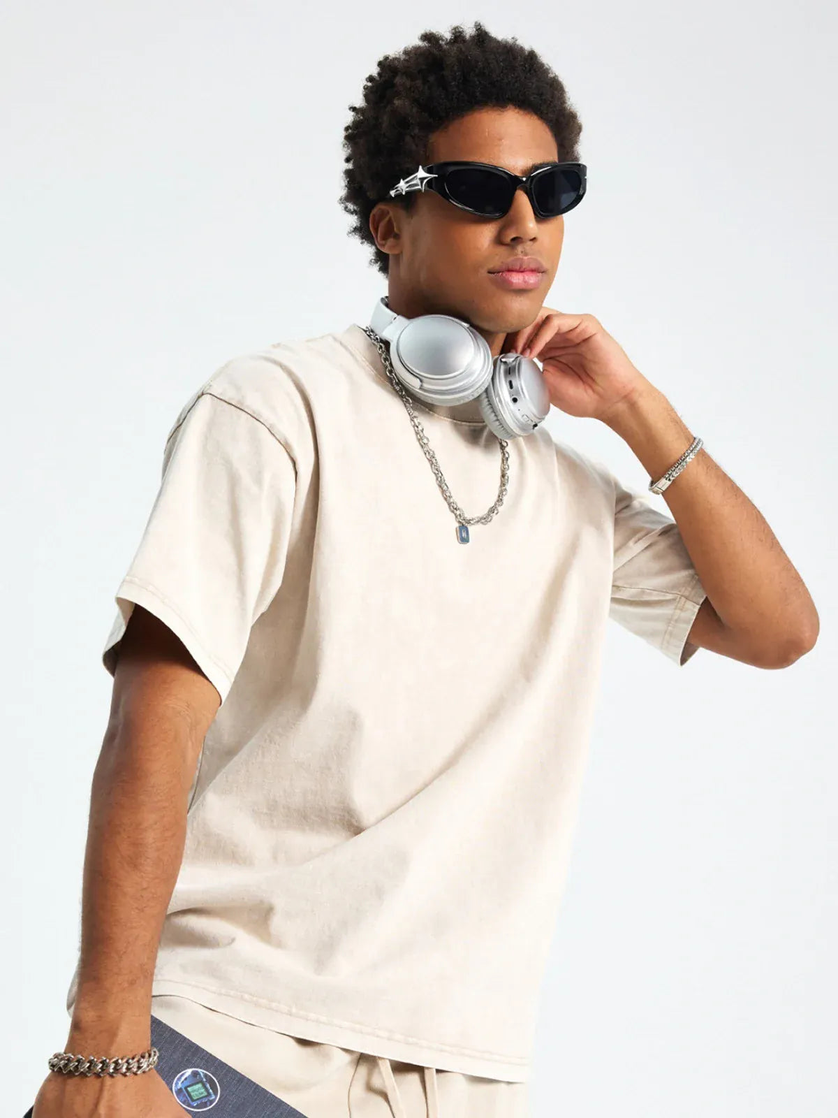 A person wearing a Custom Anime Character Beige Washed T-Shirt - Personalized Anime Style Tee, sunglasses, and silver headphones around their neck stands against a plain background.