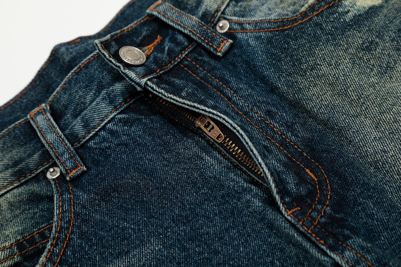 Close-up of the front zipper and button fly on dark wash jeans