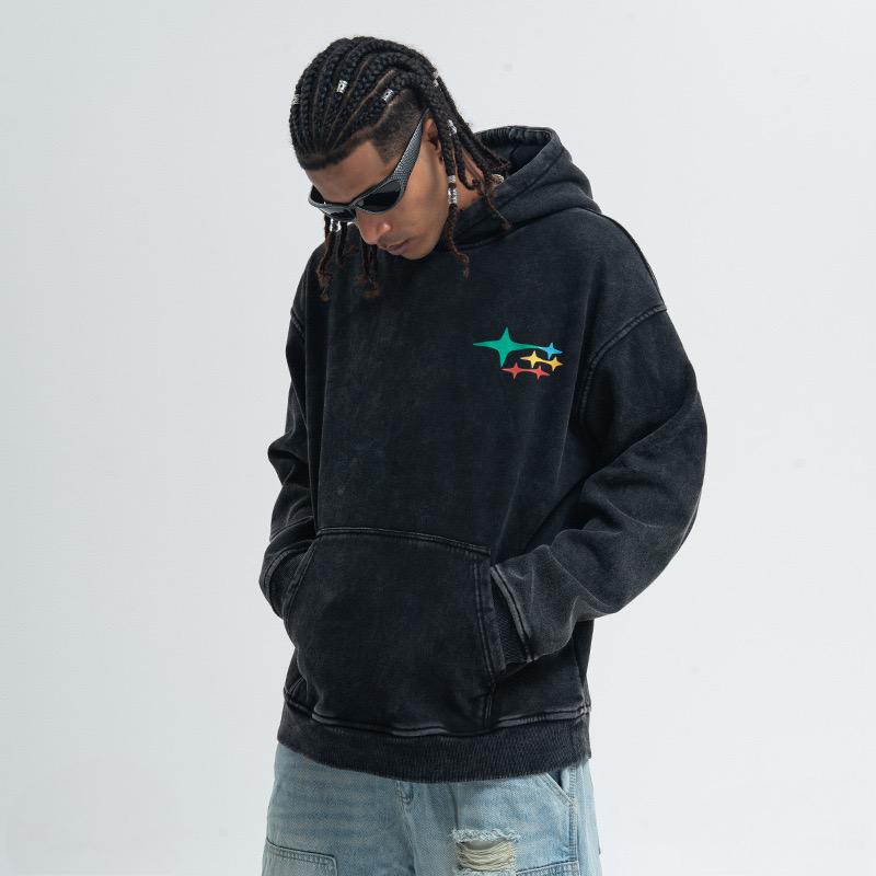 Black washed pullover hoodie with small multicolor star graphic on chest, worn with front kangaroo pocket