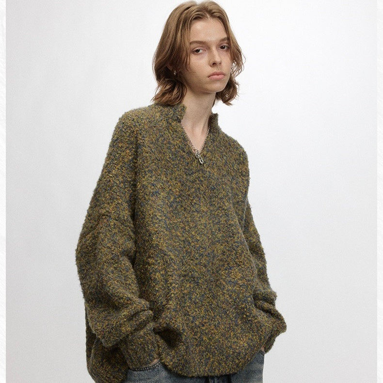 Model wearing olive and gray speckled boucle sweater with relaxed sleeves and half-zip collar