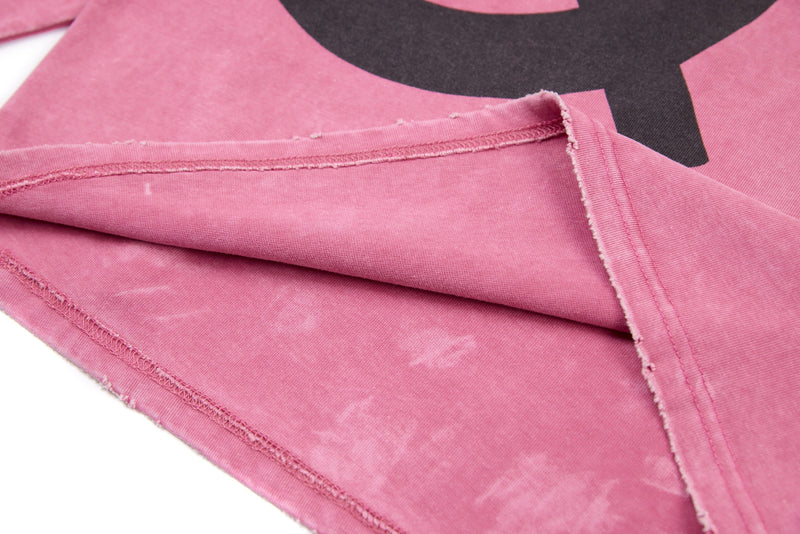 Close-up of pink tee sleeve and hem with exposed stitching and black graphic visible