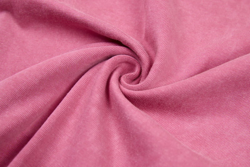 Close-up of gathered pink tee fabric showing soft cotton texture and stretch