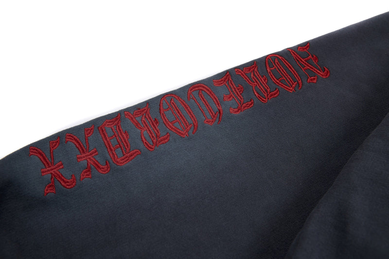 Sleeve close-up with red embroidered gothic lettering on charcoal hoodie