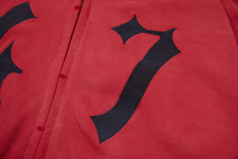 Close-up of red hoodie front with black gothic numeral graphic and zipper seam
