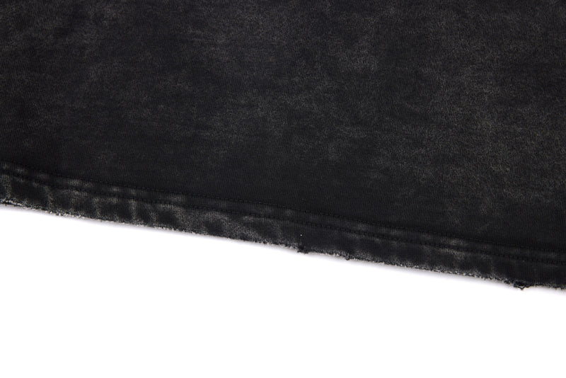 Close-up of black washed tee hem with raw edge and faded texture