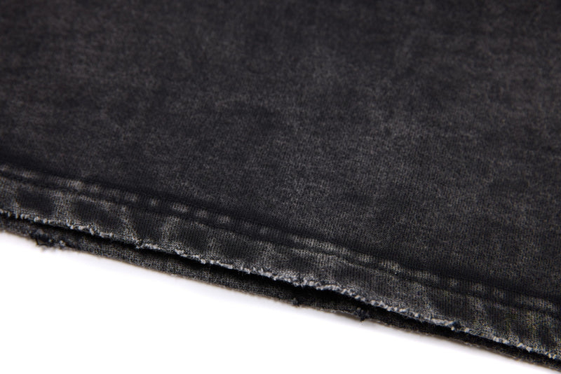 Close-up of black washed tee hem stitching and frayed raw edge