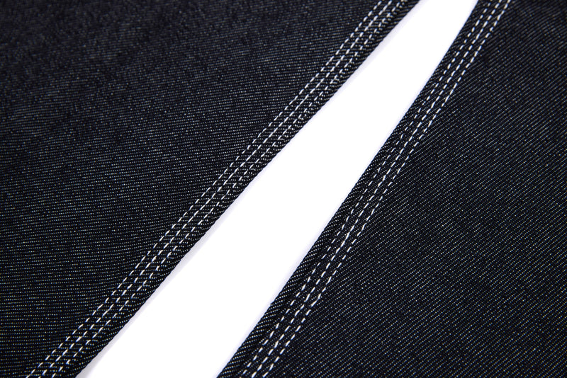 Close-up of black jeans side seam with double white topstitching