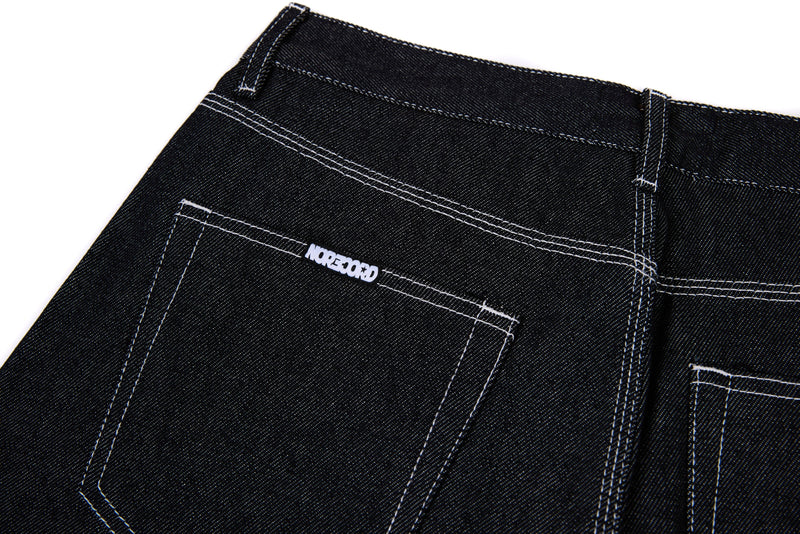 Back pocket of black denim jeans with white stitched logo detail