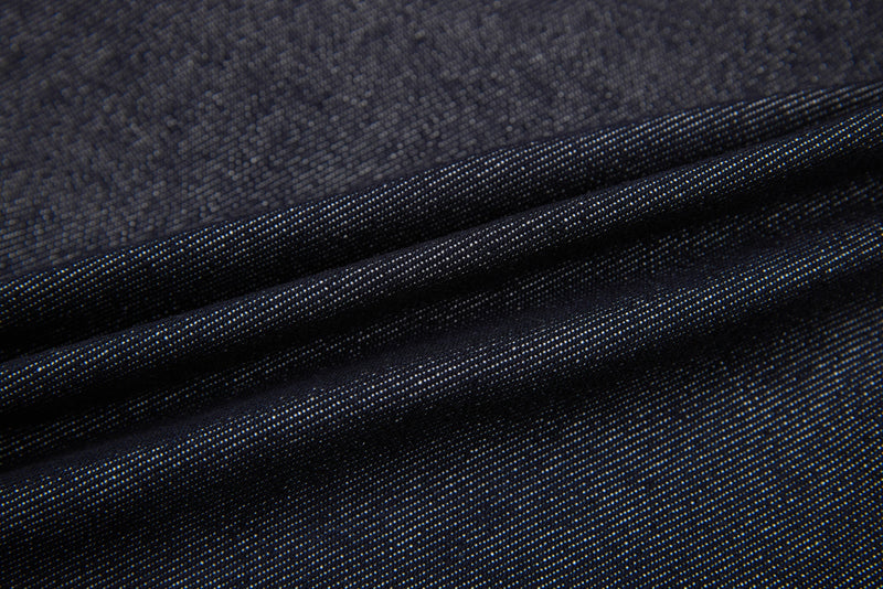 Close-up of dark denim fabric with visible twill weave and folds