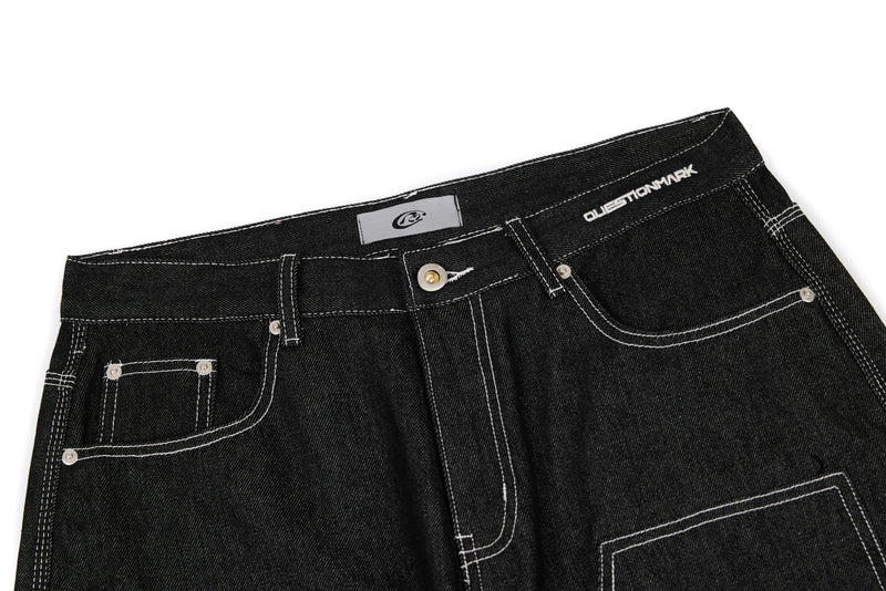 Close-up of black denim waistband with belt loops, metal rivets, and front pocket details