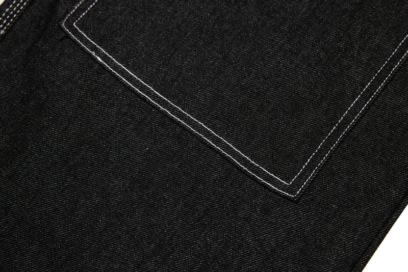 Close-up of black denim seam with white topstitching in a V-shaped panel